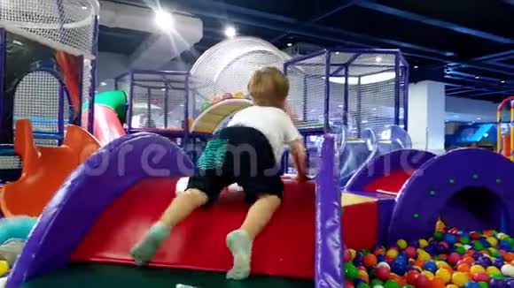 4k视频幼儿男孩爬在五颜六色的操场上上面铺着柔软的垫子以保护儿童安全视频的预览图