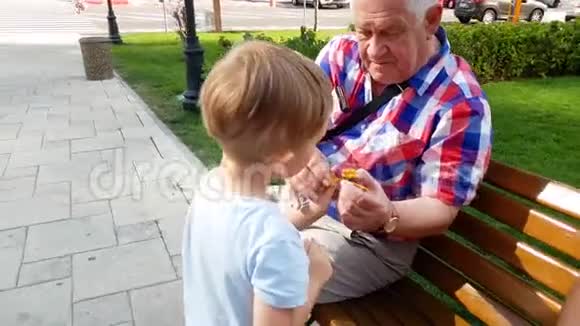 祖父带孙子在公园长椅上发射玩具直升机的4k视频视频的预览图