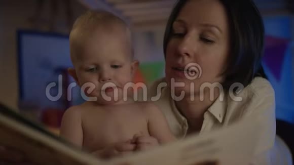 母亲给婴儿看书躺在床上贴着不同的照片给他近距离的治疗视频的预览图