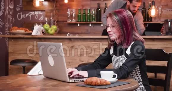 老式酒吧或咖啡店的笔记本电脑上的女士类型视频的预览图