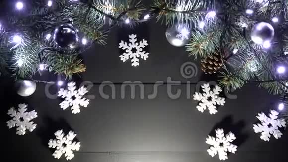 黑色木制圣诞背景顶部有松枝有灯光新年玩具视频的预览图