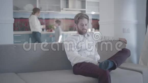 坐在客厅沙发上的一个满脸胡子的人女人和小男孩在后台家庭关系视频的预览图