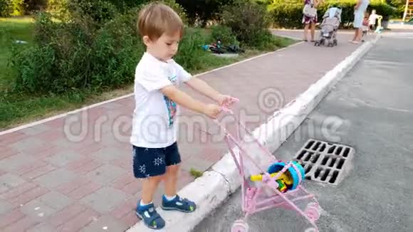 可爱的蹒跚学步的男孩带着玩具婴儿车在街上散步的4k镜头男孩为女孩玩玩具积极主动视频的预览图