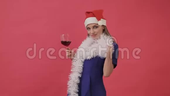 穿圣诞衣服的漂亮女孩手里拿着一杯酒跳舞工作室粉色背景视频的预览图