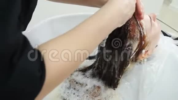女性理发前在美容院洗头及头部按摩发型师用洗发水洗头视频的预览图