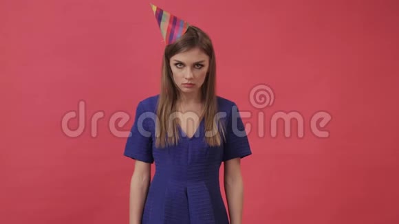 悲伤的女孩戴着节日的帽子吹着派对的哨子紫色背景工作室视频的预览图