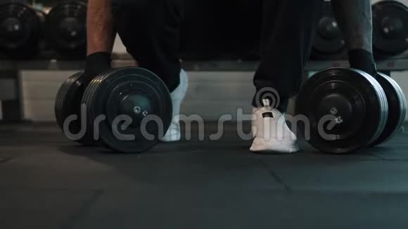 人从地板上拿起哑铃在健身房锻炼视频的预览图