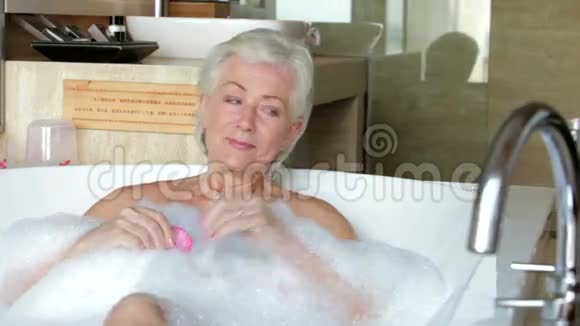 老年妇女在沐浴中放松喝香槟视频的预览图