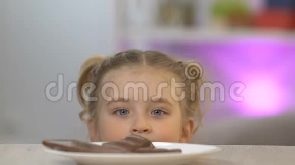 从桌子底下出现的女孩偷了一块巧克力棒甜牙视频的预览图