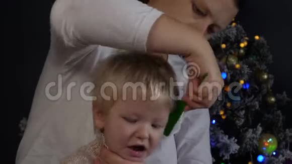 快乐的妈妈在花环上梳理着圣诞树的背景绿色的UFO火球发光的球体闪烁着视频的预览图