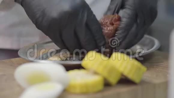 厨师手里戴着乳胶手套在金属盘子里摩擦一块小牛肉腌制肉靠近盘子的甜玉米慢动作视频的预览图