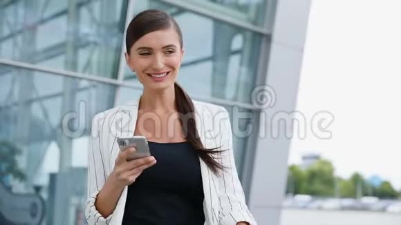 美丽的微笑商务女性使用电话在办公室附近走动视频的预览图