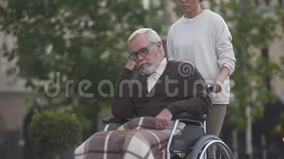 老年残疾男子在轮椅上拔罐少女手家庭支持视频的预览图