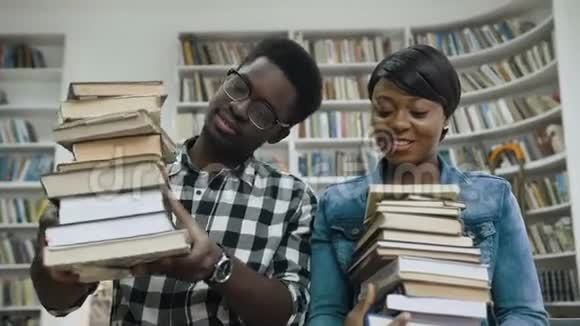 非洲男人和女孩在图书馆聊天手里拿着一堆书视频的预览图