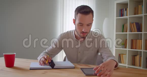 年轻英俊的白种人男学生正在学习用平板电脑看着镜头微笑的特写镜头视频的预览图