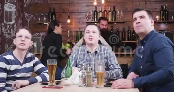 三个人在酒吧里看体育比赛视频的预览图