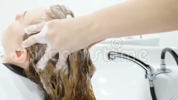 女性理发前在美容院洗头及头部按摩发型师用洗发水洗头视频的预览图