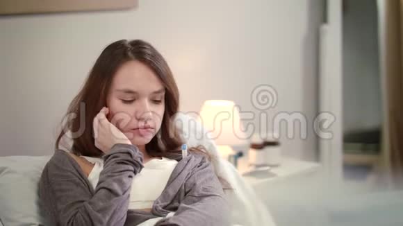 生病的女人在床上测量温度卧室里感冒的女人视频的预览图