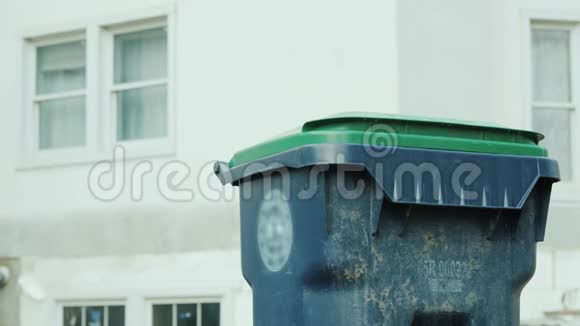 一个男人把一袋垃圾扔进他家附近的垃圾箱视频的预览图