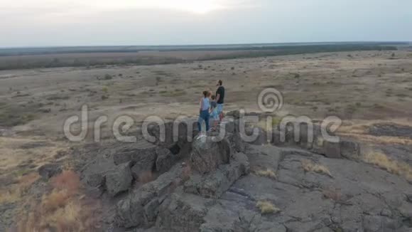 空中观景一家人站在山上母亲父亲和儿子去山里远足日落视频的预览图