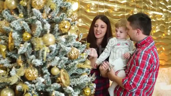 幸福的家庭有一个蹒跚学步的女儿在家里给圣诞树做装饰品视频的预览图