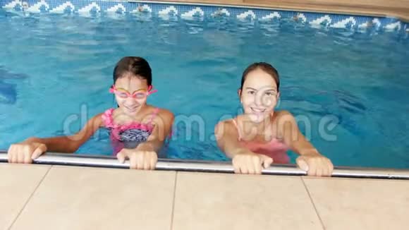两名身穿彩色泳衣的少女在室内游泳池游泳的4k录像视频的预览图