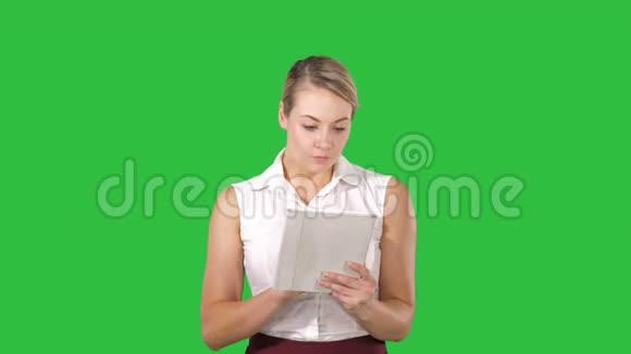 美丽的金发美女正在用她的数码平板电脑观看绿色的照片和视频视频的预览图