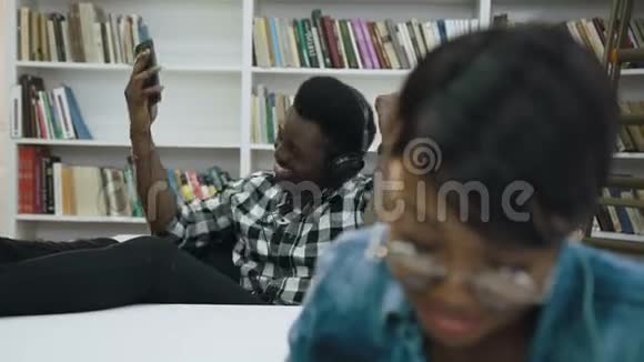 非洲男学生使用智能手机而另一名女学生准备考试视频的预览图