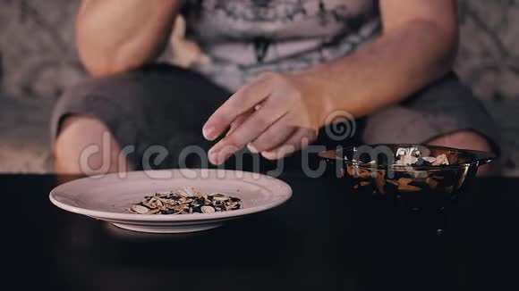 那个人把站在桌子上的杯子里的种子拿出来把它们从外壳里清理出来那人把皮扔进盘子里视频的预览图