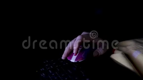 黑暗房间里的女孩用鼠标控制笔记本电脑一只手的特写里面有一只老鼠视频的预览图
