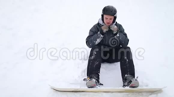 为了安全而戴头盔的滑雪板坐在雪地上视频的预览图