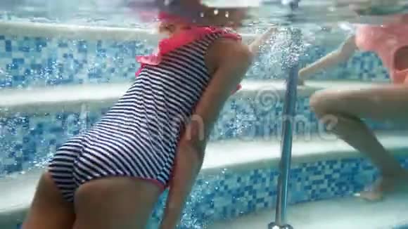 两名身穿彩色泳衣的少女在室内游泳池游泳的4k录像视频的预览图