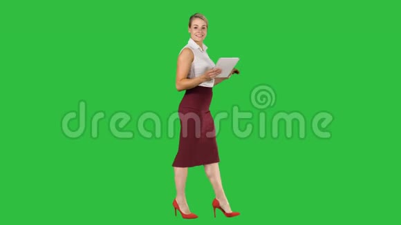 女人用数字平板电脑走路在绿色屏幕上与相机交谈Chroma键视频的预览图