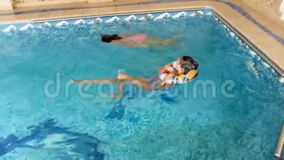 两个女孩在游泳池里玩耍的4k镜头孩子们在水里嬉戏打闹视频的预览图