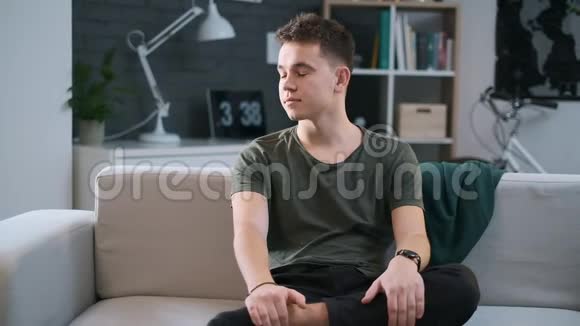 一个可爱的男孩坐在他时髦的房间里的沙发上视频的预览图