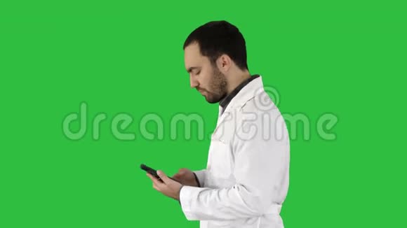 英俊的男性健康护理专业人员或医生或护士的特写肖像在绿色屏幕上用手机发短信视频的预览图