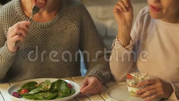 享受甜点的女人嘲笑朋友吃沙拉垃圾食品和医疗保健视频的预览图