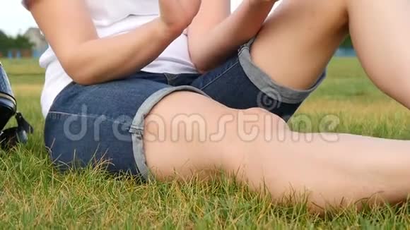 女孩坐在绿草上使用智能手机一个年轻的女人使用社交网络特写视频的预览图