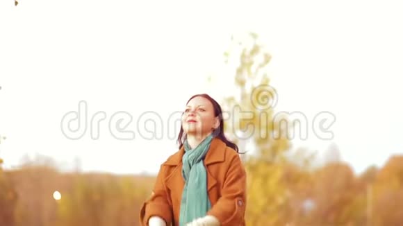 公园里的一个年轻女子在秋天把枫叶扔到空中慢动作视频的预览图