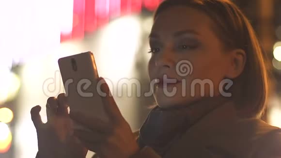年轻女性在广告牌背景上滚动智能手机应用程序视频的预览图