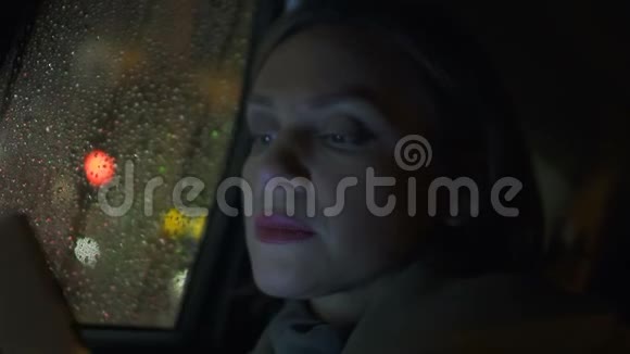 女士阅读智能手机信息在雨天乘坐出租车申请视频的预览图