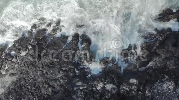 黑色火山海滩的空中拍摄波浪撞击岩石形成天然喷泉视频的预览图