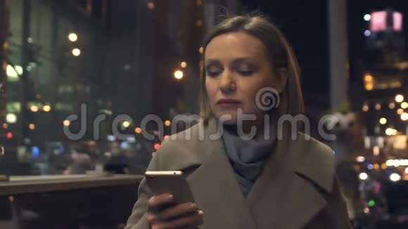 优雅的年轻女士在城市大街上散步时在智能手机上阅读信息视频的预览图