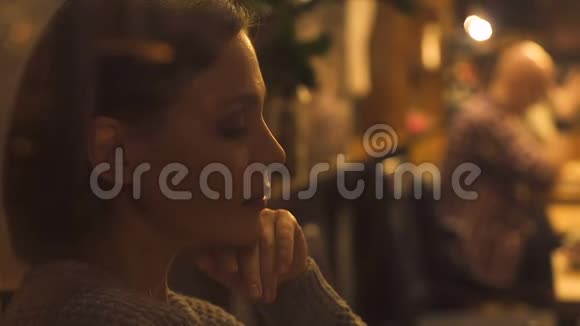 年轻漂亮的女人悲伤地叹息坐在咖啡馆里看着顾客孤独视频的预览图