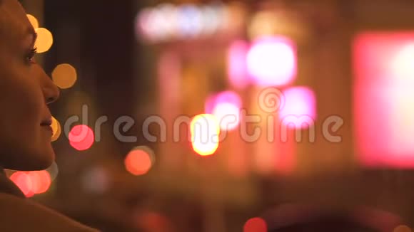 迷人的黑发女士看着夜晚的城市灯光巨大的照明视频的预览图