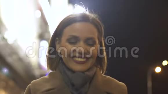 30多岁的幸福微笑的女人在灯火辉煌的城市街道上傍晚的长廊上视频的预览图