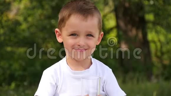 大自然中的一个孩子从杯子里喝果汁这个男孩喜欢喝健康的饮料视频的预览图
