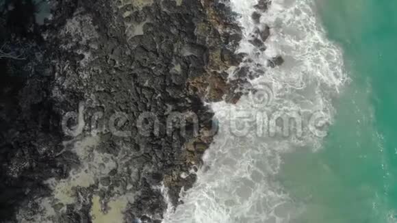 黑色火山海滩的空中拍摄波浪撞击岩石形成天然喷泉视频的预览图