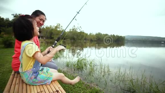 母亲和女儿在湖边钓鱼幼儿与自然联系的概念视频的预览图