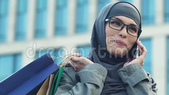 穆斯林妇女在智能手机上与朋友交谈吹嘘购物特写视频的预览图